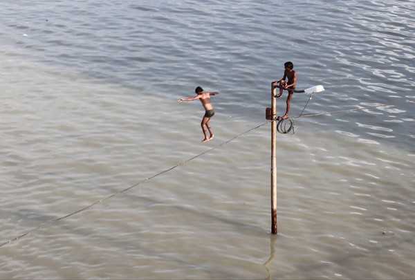 [Фото дня] Діти стрибають у воду, що зібралася на вулиці в результаті повені. Індія